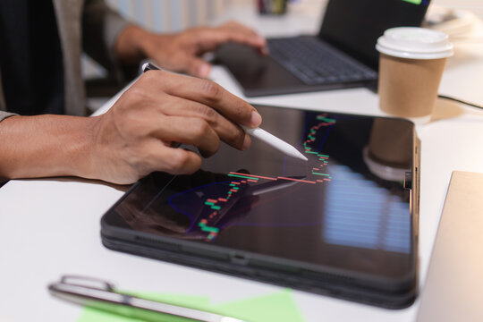 Professional trader analyzing stock market charts on laptop, tablet, and monitor while reviewing candlestick patterns, technical indicators, and market trends to support informed investment decisions.