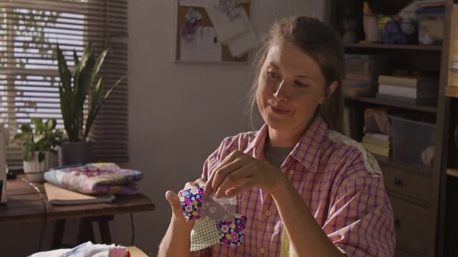 Caucasian woman showing colorful fabric squares to friend during quilting workshop, camera tilting down. Clip is ideal for DIY craft tutorials and creative hobby advertisements