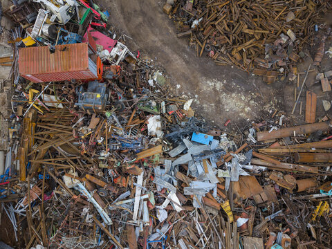Aerial view of a scrap metal recycling yard in Agnesberg featuring piles of rusted steel beams, discarded machinery, and a shipping container in Gothenburg, Vastra Gotaland, Sweden.