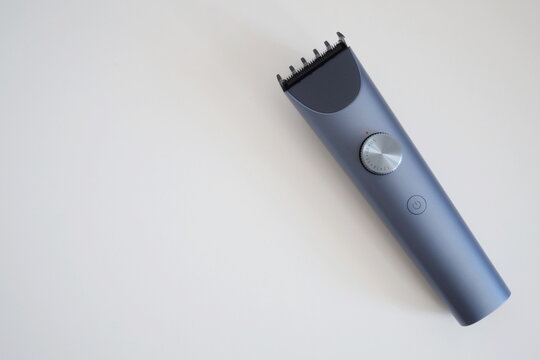 Modern wireless hair clipper with short comb attachment on white background