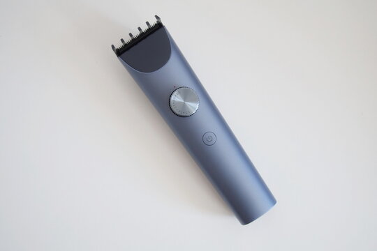 Modern wireless hair clipper with short comb attachment on white background