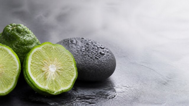 Fresh makrut lime with wet black spa stone and copy space