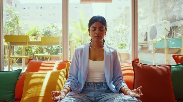 Beautiful indian business woman working in a coworking company office. Meditation and yoga in the break time.