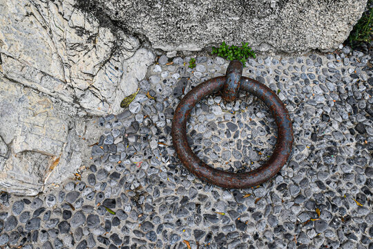 Old rusty iron mooring ring on a traditional stone pebble pavement in Camogli harbor, Liguria, Italian Riviera, Italy