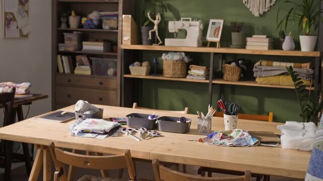 Empty wooden table in creative sewing workshop displaying fabrics, scissors, and tools during slow zoom in. Footage is perfect for promoting DIY craft classes or fashion design schools
