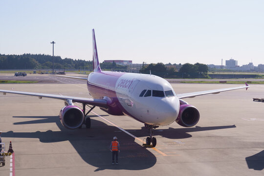 Peach Aviation Airbus A320 faces the camera head-on at the apron as a ground marshaller stands by on November 4, 2024 in Narita International Airport, Narita, Japan.