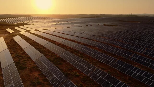 Aerial view of an extensive photovoltaic field illuminated by warm sunset light.