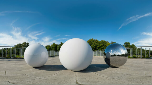 Minimalist geometric spheres on concrete terrace, white and chrome 3D balls under blue sky, modern architectural outdoor sculpture