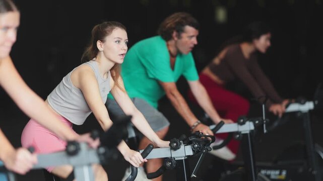 Athletic woman in a top and leggings is pedaling an exercise bike in the gym. European woman doing a cardio circuit workout on the machine during a Crossfit workout 