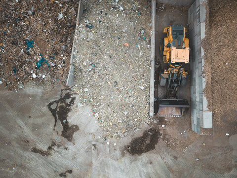 Aerial view of a yellow front-end loader operating at a waste management facility in Agnesberg, Gothenburg, Vastra Gotaland County, Sweden.