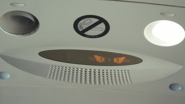 Airplane overhead panel with seat belt and no smoking signs above passenger seats. High quality 4k footage