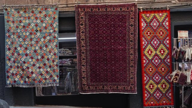 Traditional Turkish carpet shop displaying colorful handmade oriental rugs with geometric patterns and intricate designs in a local market. High quality 4k footage