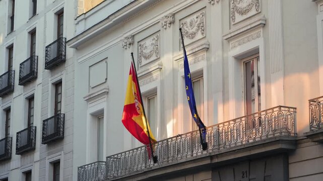 Spanish flags flying on the rooftop of a historic white building under a clear blue sky. Spain, national identity, government and travel concept. High quality 4k footage