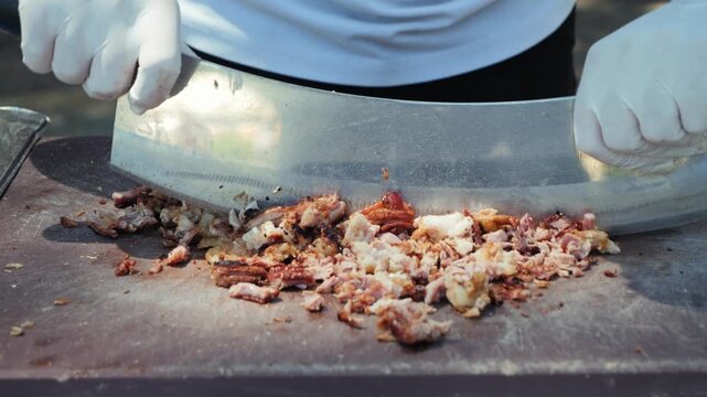 Traditional preparation of kokorec with lamb intestines being finely chopped with a large knife on a cooking surface. High quality 4k footage