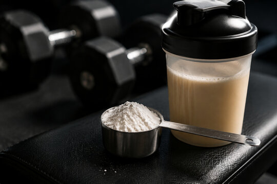 Stainless steel scoop with creatine powder and protein shake, fitness supplement concept