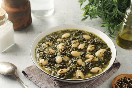 A bowl with traditional Tuscan kale salad and white beans soup Cavolo nero e fagioli