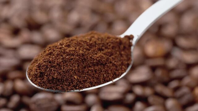 Macro photography A spoon of natural ground coffee, against the background of coffee beans. Coffee. An invigorating drink. The texture of coffee beans. Smooth circular movement