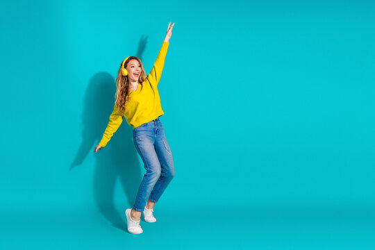 Young woman dancing in yellow sweater against blue background with headphones conveys bright lifestyle fashion mood