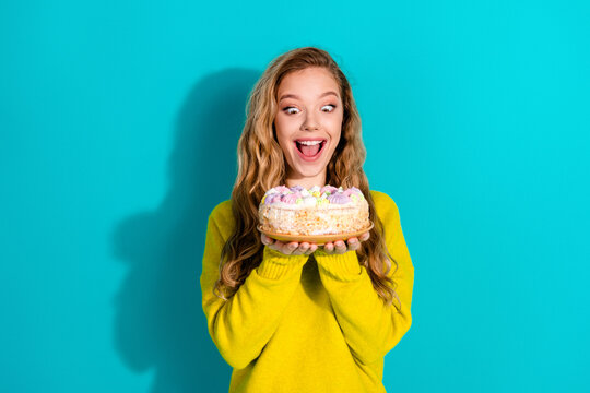 Happy young woman celebrates birthday with cake against bright blue background