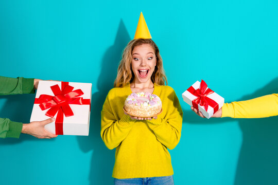 Young woman in yellow sweater celebrates birthday with cake and gifts as friends present colorful party scene