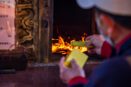 Taichung, Taiwan, January 28, 2025: Close-up of a traditional Taiwanese temple ritual involving burning joss paper and devout worshippers.