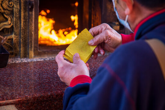 Taichung, Taiwan, January 28, 2025: Close-up of a traditional Taiwanese temple ritual involving burning joss paper and devout worshippers.