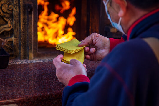 Taichung, Taiwan, January 28, 2025: Close-up of a traditional Taiwanese temple ritual involving burning joss paper and devout worshippers.