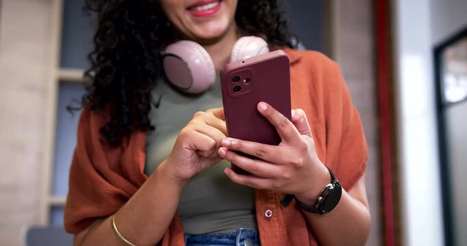 African American woman receiving alert, tapping phone and smiling at office replying to messages
