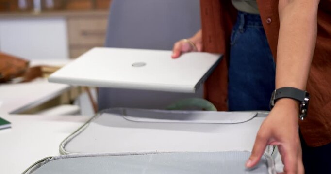 African American woman in cardigan at table opening green case, placing silver laptop for travel