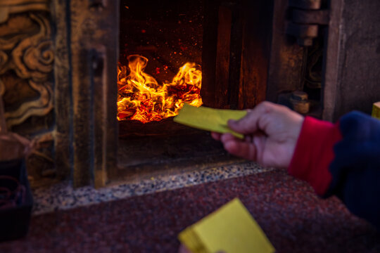 Taichung, Taiwan, January 28, 2025: Close-up of a traditional Taiwanese temple ritual involving burning joss paper and devout worshippers.