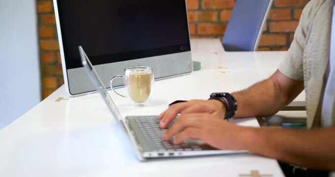 Man typing on laptop spotting call alert, donning headphones, joining call at desk, copy space