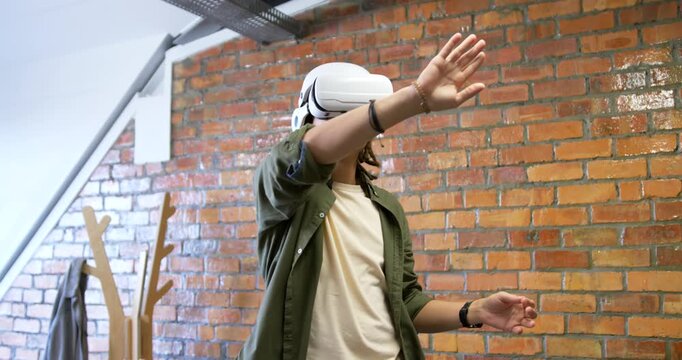 African American male wearing white VR headset in loft responding to virtual prompts, gesturing