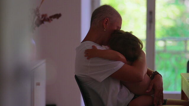 Mother with cancer embracing toddler child at home, sharing candid affectionate moment, expressing unconditional love, resilience, family bonding, caregiving and hope