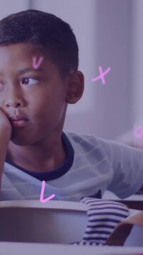 Animation of letters over bored schoolboy at desk in classroom