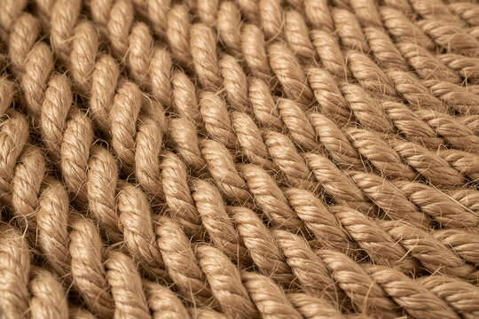 Close-up texture of a woven natural jute rope rug in beige and tan tones.