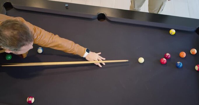 Diverse males playing pool, man in jacket lining, striking cue ball breaking rack, copy space