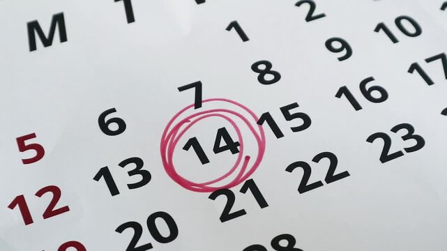 A close up view of a calendar page with the fourteenth day circled in red ink.
