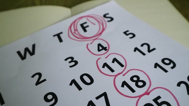 A paper calendar with specific dates circled in red ink for planning.