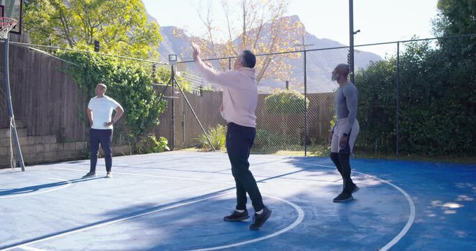 Diverse men playing on blue court with hoodie walking, dribbling shooting ball bouncing retrieving