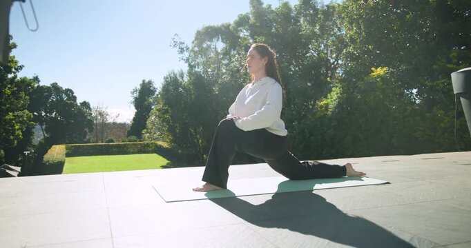 Woman doing yoga on terrace mat, starting low lunge, shifting forward, folding to stretch hamstring