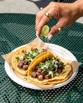 Hand Squeezing Fresh Lime over Authentic Mexican Carne Asada Street Tacos