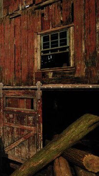 The barn has a weathered red wooden exterior. Logs are stacked near the entrance, and a small window is visible above. This scene is in a rural area with natural surroundings.