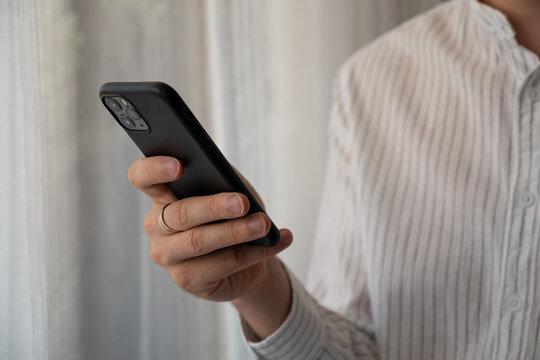 Man holding smartphone near window, close up of mobile communication and modern digital lifestyle at home