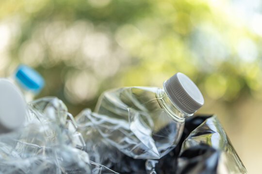 crushed plastic bottles on green bokeh nature background, recycling and zero waste concept
