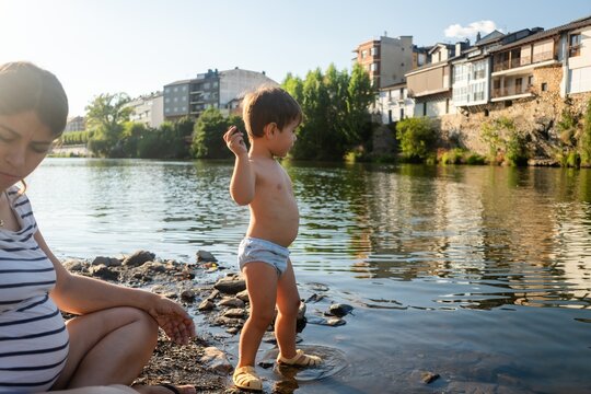 A toddler white boy throwing a rock