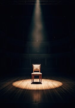 Distant chair centered in circular spotlight on theater stage.