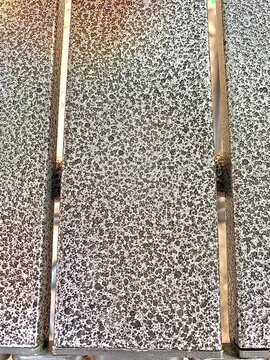 rusty metal background Macro close-up of parallel metal bars with a speckled hammered paint finish. The surface features a textured pattern of black and silver dots, giving it an industrial