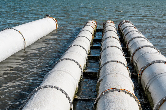 Large industrial pipes over water, part of marine infrastructure and engineering. Horizontal color photo. Macro