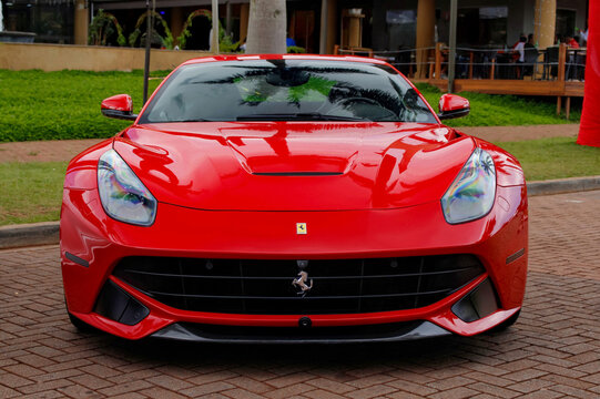 Red Ferrari F12berlinetta centered front view, Italian Luxury supercar on brick pavement outdoors