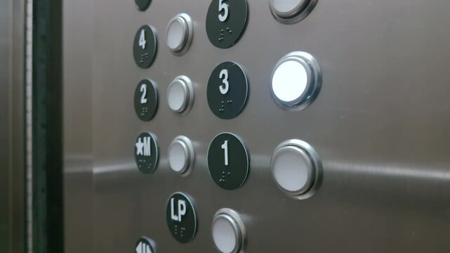 Elevator control panel with glowing third floor button and braille indicators